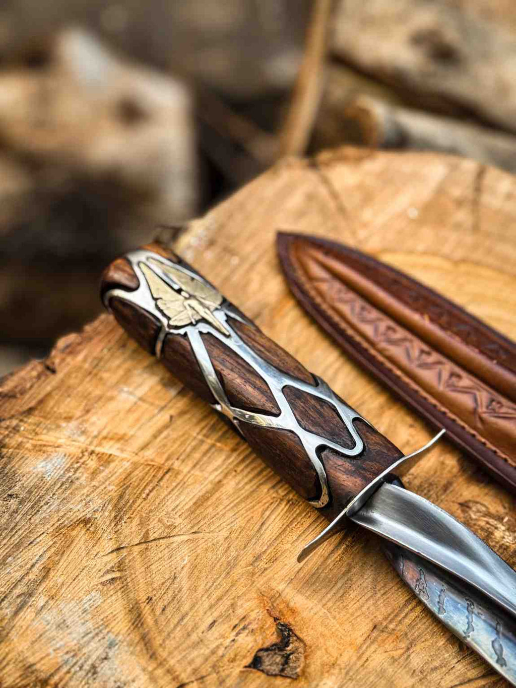 Close-up macro view of a handcrafted Subtle Knife replica handle showing intricate silver metalwork and gold inlay details on dark wood, resting on a rustic log for USA fantasy collectors.