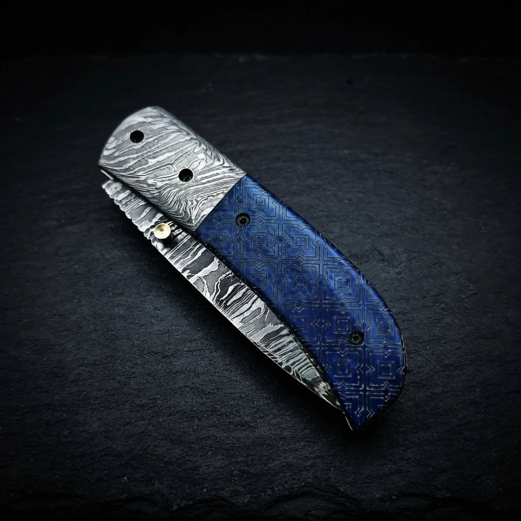 Alien graphic folding knife — drop point Damascus blade close-up
