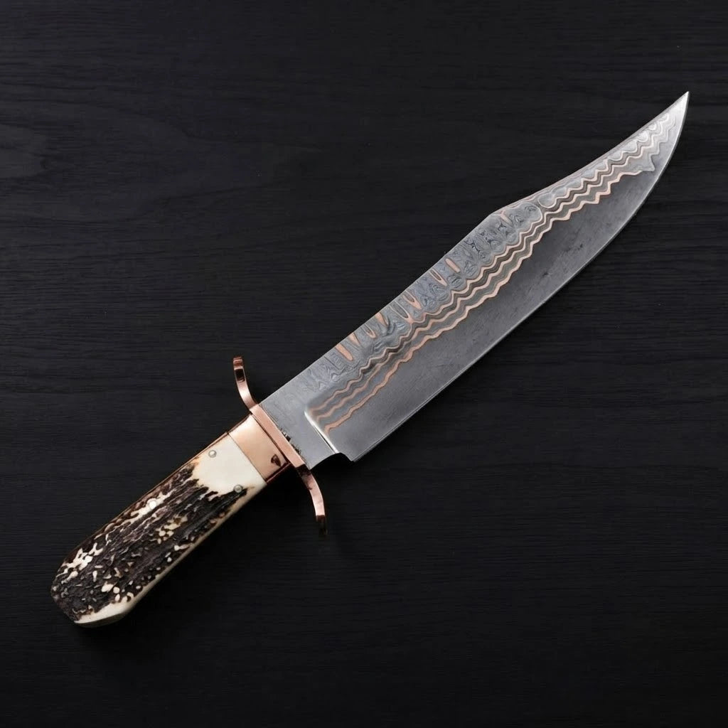 A 12-inch Copper Damascus Bowie knife with a copper double guard and textured stag antler handle, angled on a dark wood background