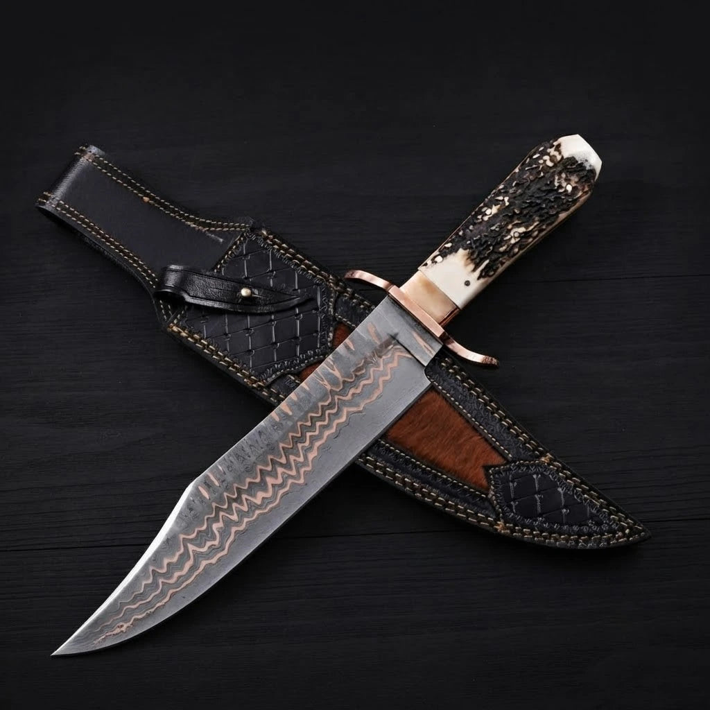 A 12-inch Copper Damascus Bowie knife with a copper double guard and textured stag antler handle, crossing over its black leather sheath on a dark background