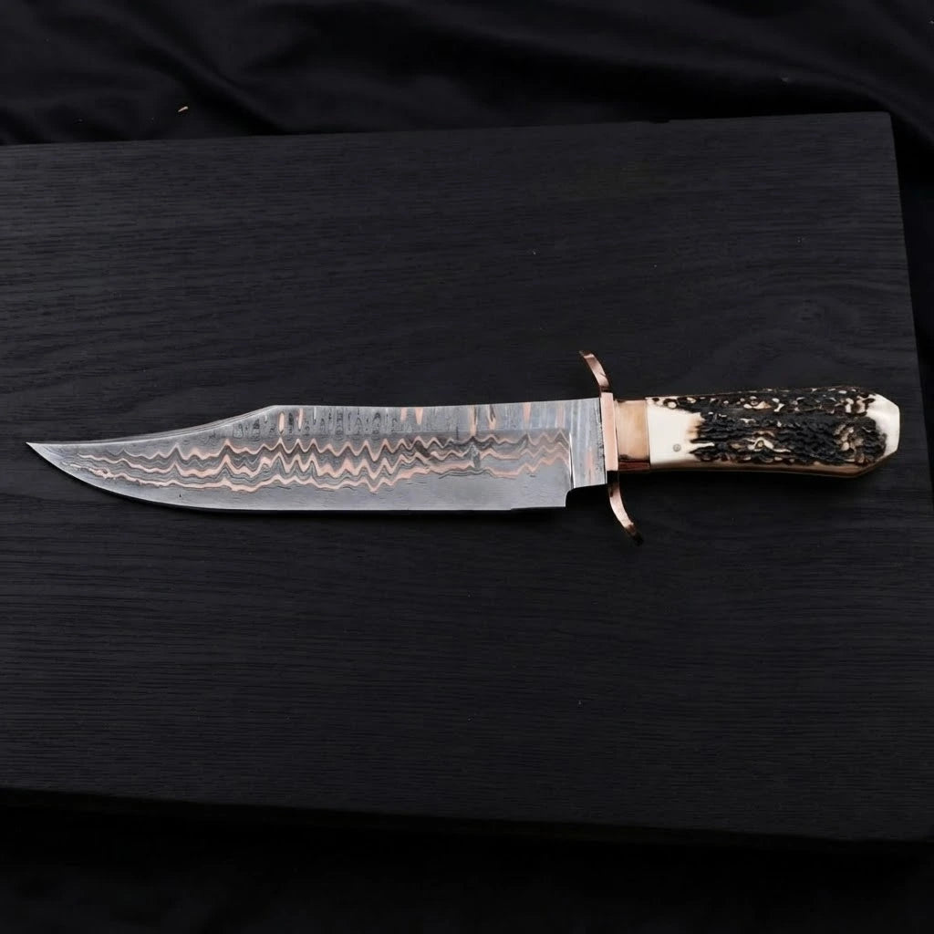 Horizontal view of a 12-inch Copper Damascus Bowie knife with a copper double guard and a textured stag antler handle on a dark wood background