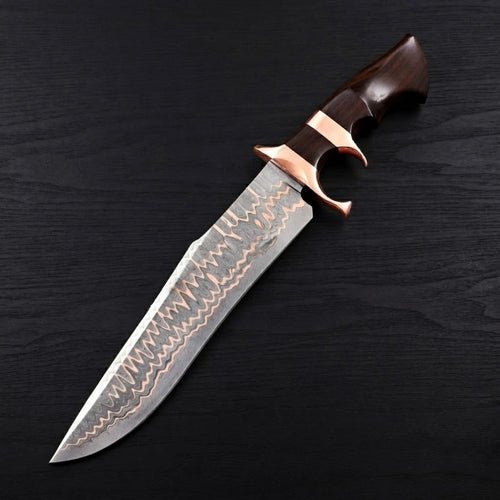 A solo diagonal view of a Copper Damascus Bowie knife showcasing a double copper guard and a dark ebony wood handle on a dark wood background