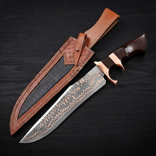 Copper Damascus Bowie knife with a double copper guard and dark ebony wood handle next to its brown leather sheath on a dark background