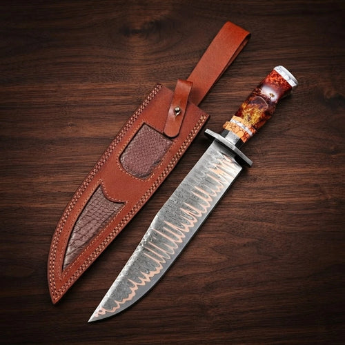 A handcrafted Copper Damascus steel Bowie knife featuring a long clip-point blade with visible copper layers, a dark metal handguard, and a hybrid fire-resin and faux stag horn handle, displayed next to its custom brown leather sheath with alligator-skin texture inserts on a dark wood background.