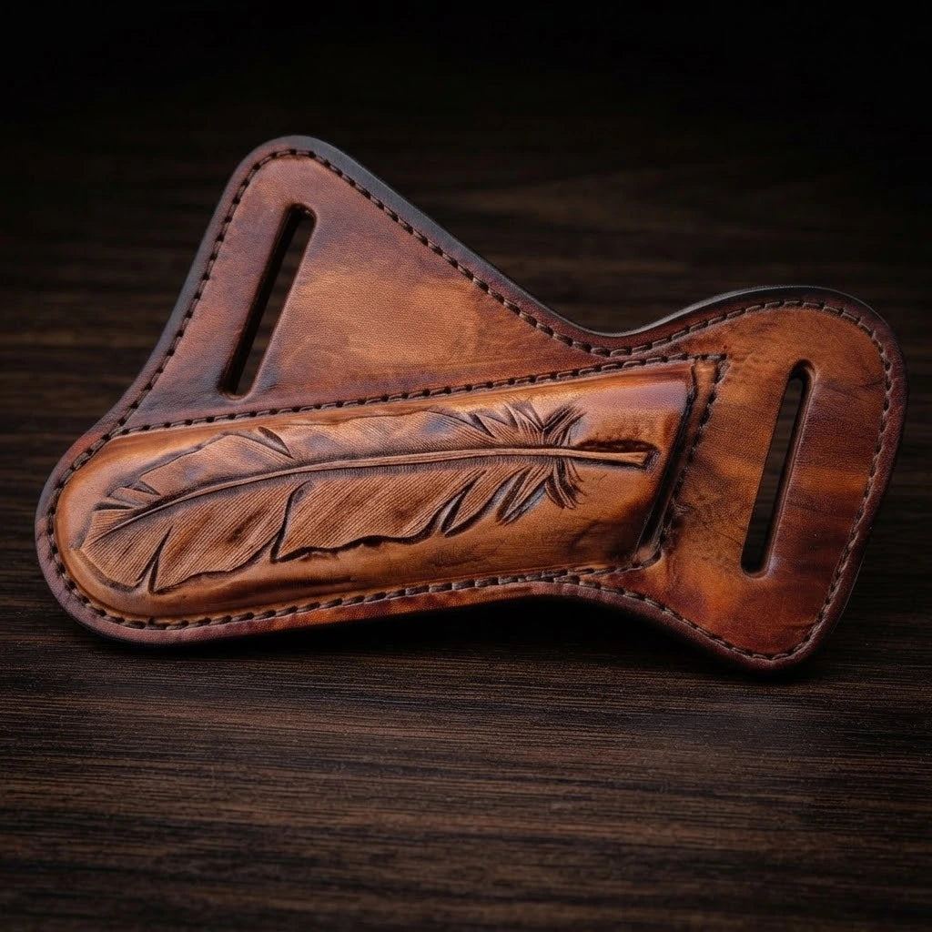 A brown hand-tooled leather pancake sheath for a cowboy belt knife, featuring a highly detailed carved feather design in the center, neat perimeter stitching, and two belt loops, displayed flat on a dark wood background.
