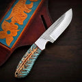 A full side profile of a custom handmade Bowie knife featuring an intricate Damascus steel blade with a scalloped edge and thick brass spine plate, a polished curved brass crossguard, and a smooth white bone handle on a dark wood grain background.