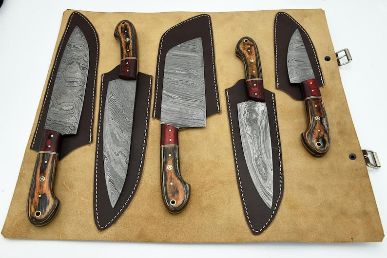 5-piece Damascus steel kitchen knife set with resin wood handles, each fitted in individual brown leather sheaths laid open on a tan leather chef roll storage bag