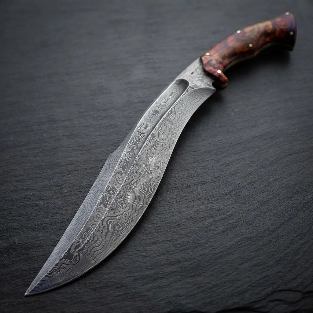 Handcrafted full tang Damascus steel Kukri knife featuring a contoured rosewood burl handle, resting diagonally on a dark slate stone surface