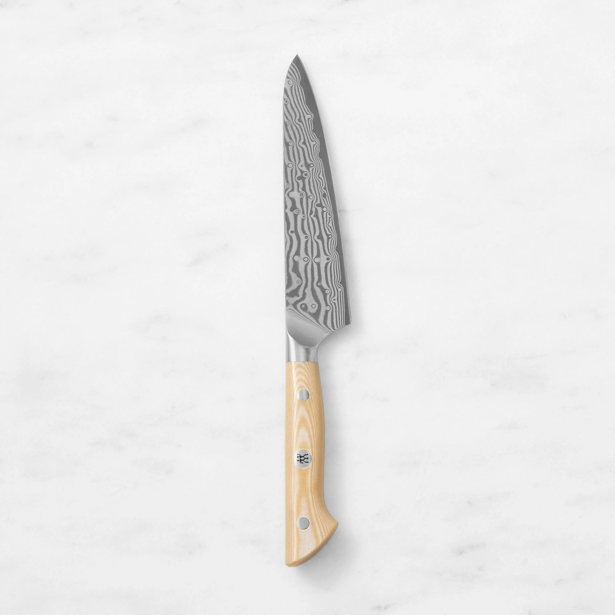 Damascus steel utility prep knife with a natural light wood handle and mosaic pin, centered vertically against a smooth white marble background.