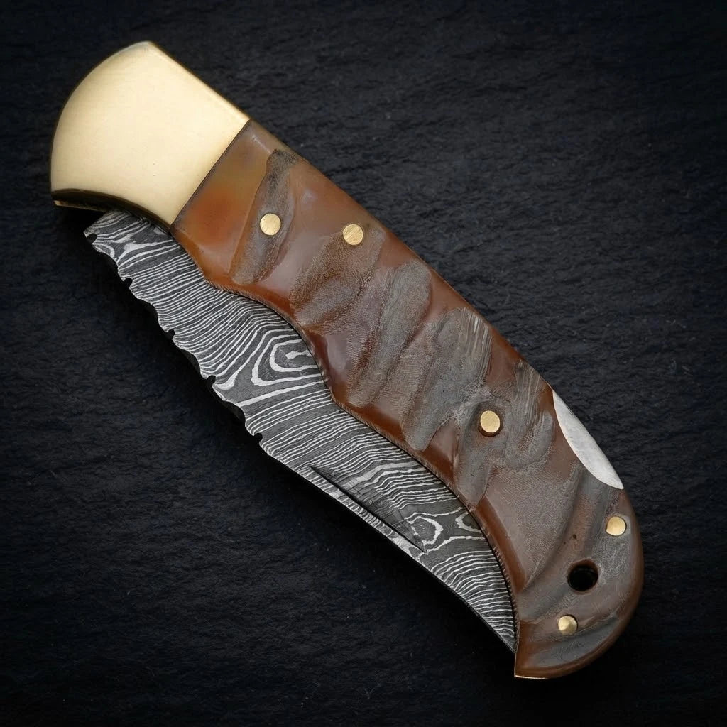 Damascus EDC folding knife with ram horn handle and brass bolster – folded with sheath
