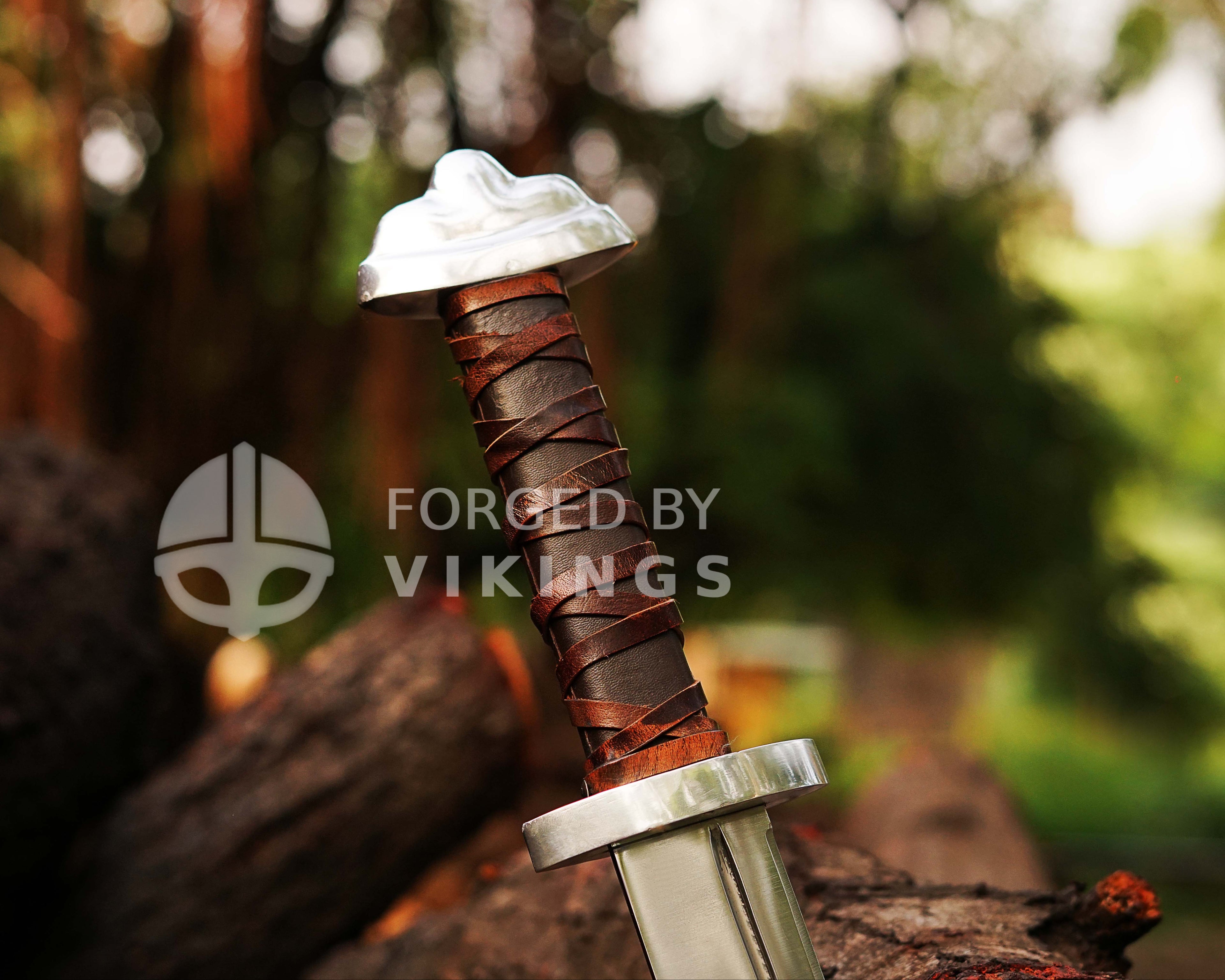 Hand-forged Viking Seax knife with detailed blade engravings resting on wooden logs