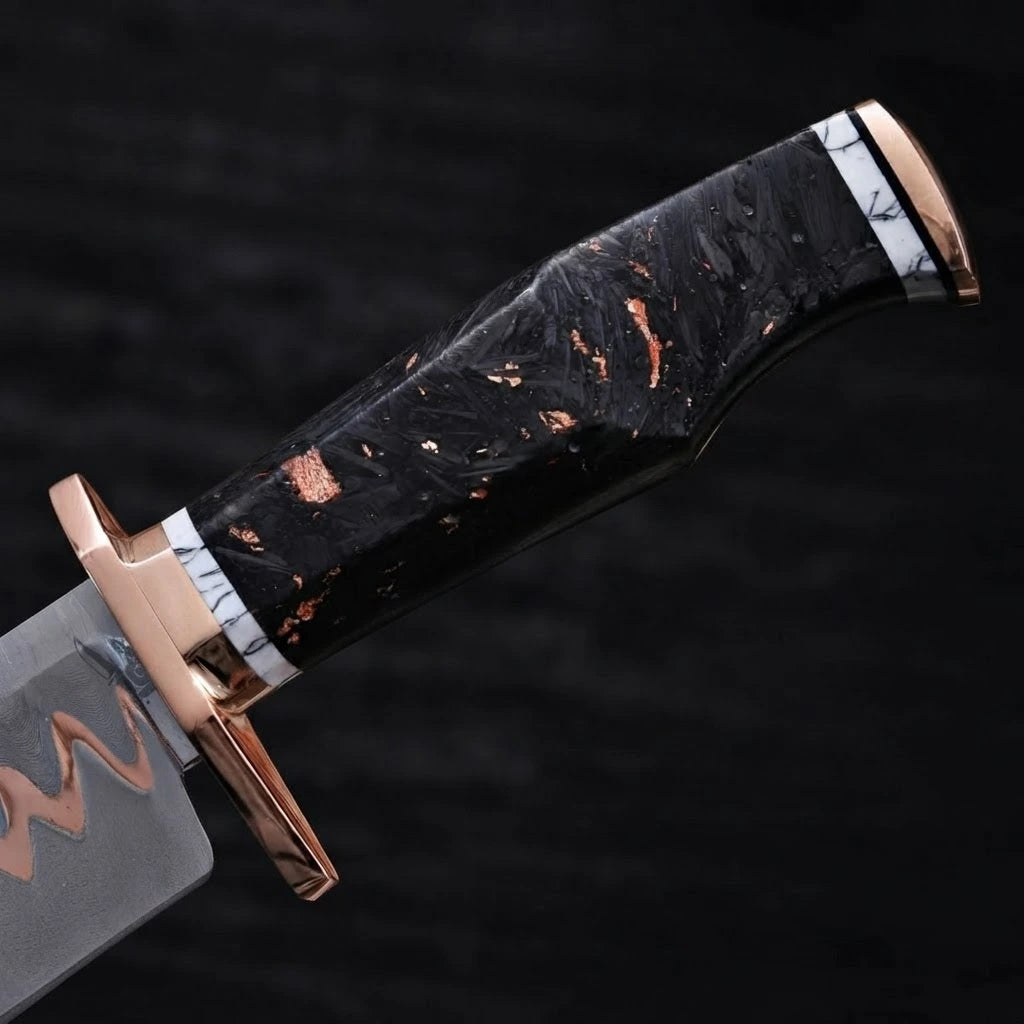 Close-up of a Bowie knife handle featuring a polished copper guard, marbled black resin grip with copper flakes, and white marble accents on a dark background
