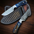 A matching custom handmade knife set featuring one rasp steel blade with textured cross-hatch filework and one patterned Damascus steel blade, both styled with polished metal bolsters and vibrant blue-dyed pine cone hybrid resin handles, displayed over a basket-weave tooled brown leather double pancake sheath on a dark wood background
