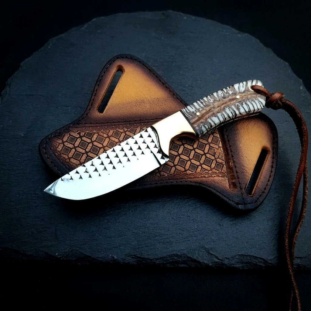 Handmade rasp steel cowboy knife featuring a brass bolster, pine cone scale handle, and leather lanyard, showcased horizontally with a geometrically stamped leather crossdraw holster