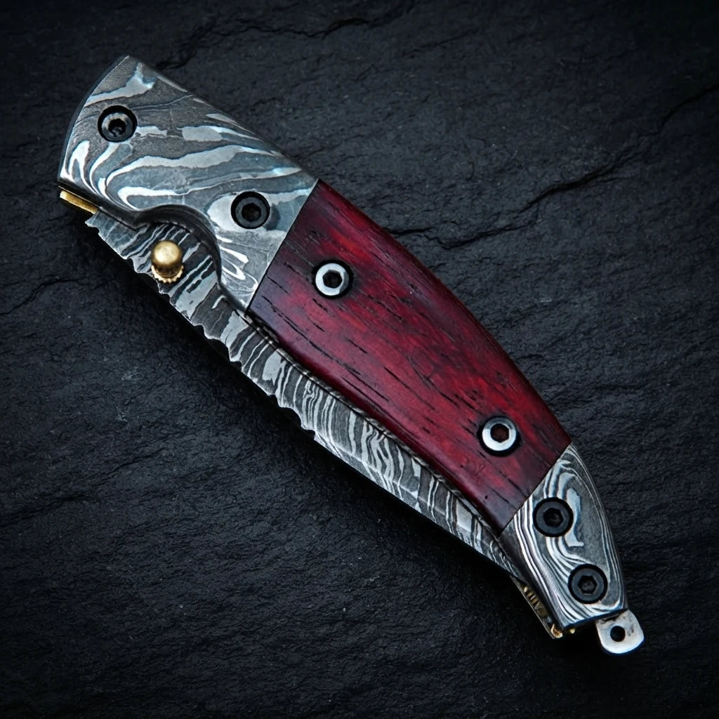 Damascus steel bolster and blade detail on red blood wood handle knife