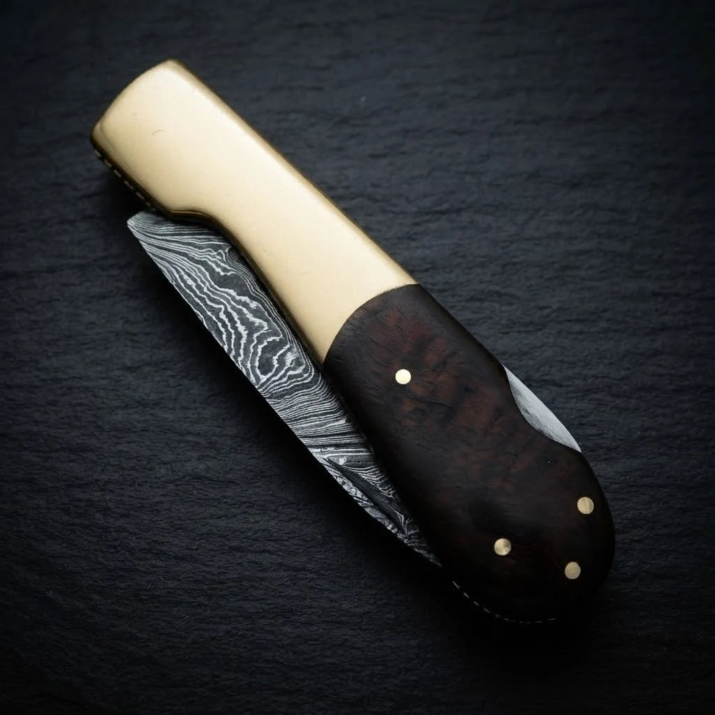 Damascus folding knife — brass bolster and sabre grind blade detail